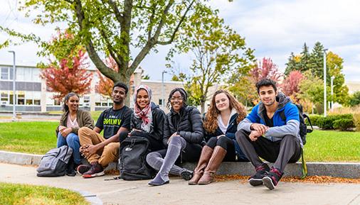 学生s sitting on sidewalk on campus